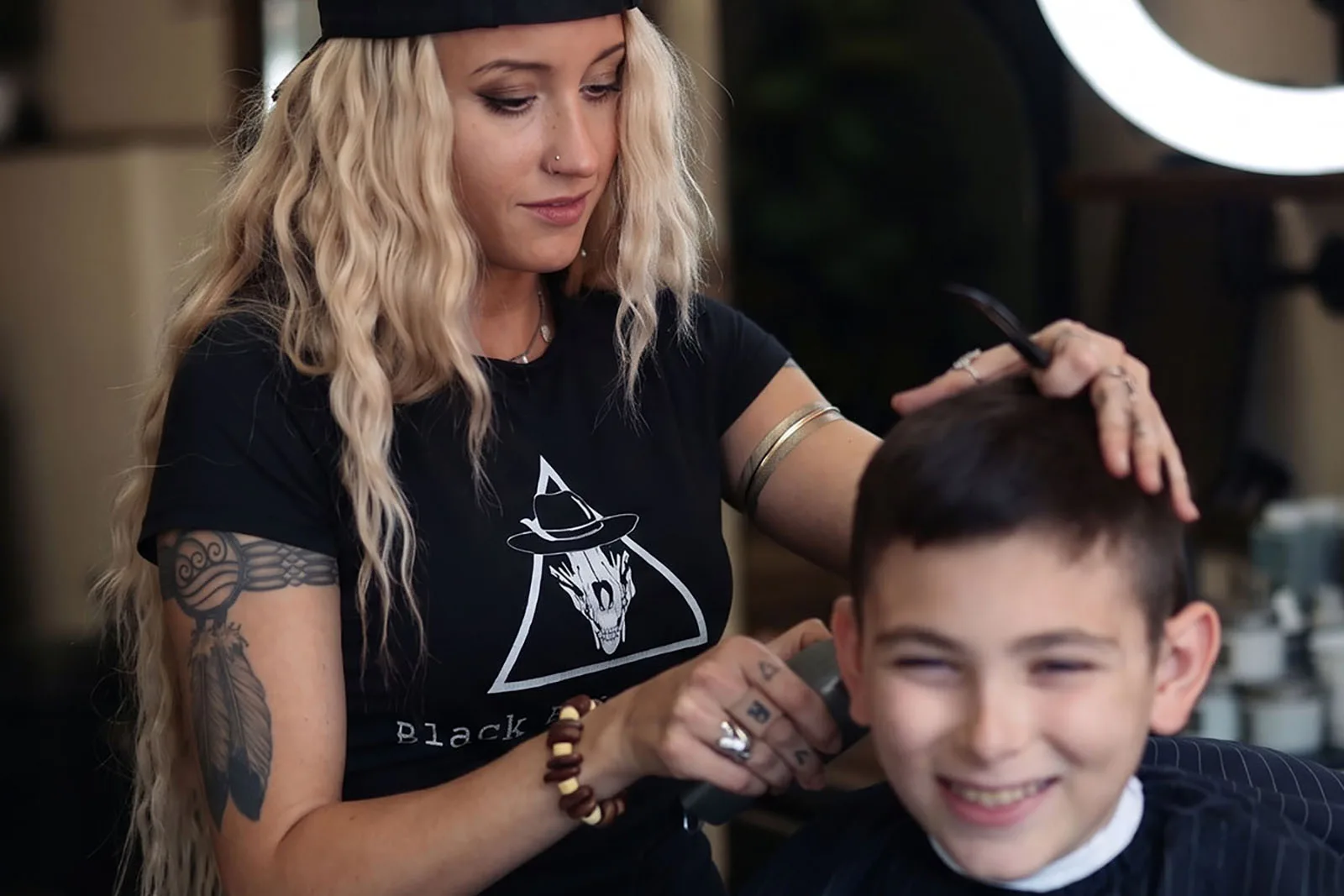 Master barber Ren Faith settling in a young client before a haircut at Black Hat Barber, downtown Willoughby Ohio